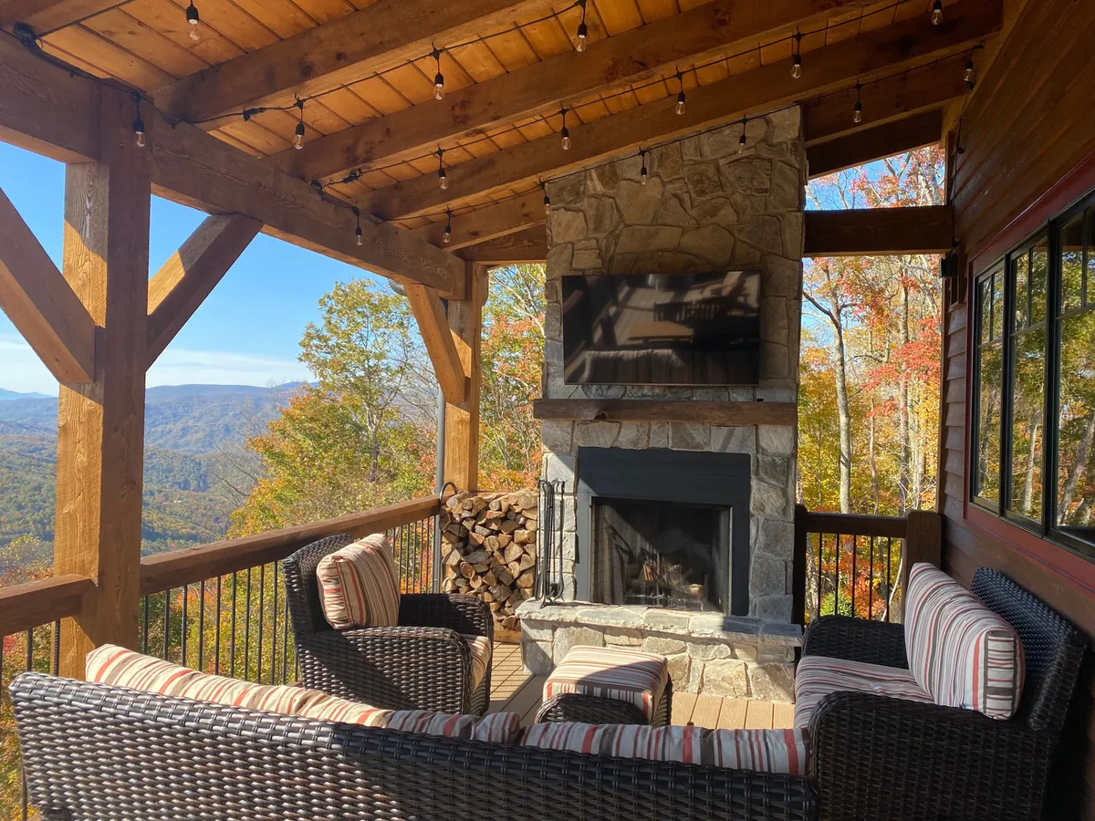 A luxurious outdoor seating area facing a stone fireplace, framed by mountain views. The setup suggests gatherings, outdoor relaxation, or even onsite events such as wine tastings or summer concerts, with plush seating and an inviting ambiance.