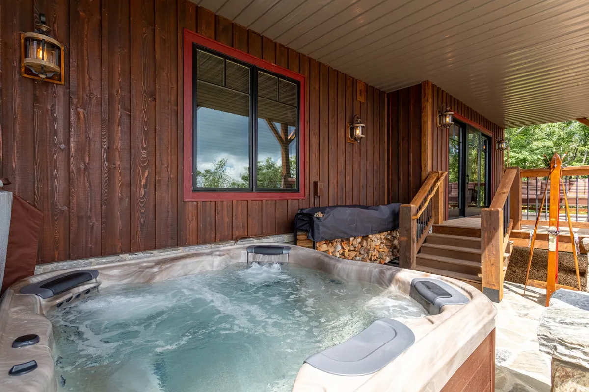 An inviting outdoor hot tub set against the wooden exterior of the home, perfect for relaxing after a day of family activities. The tranquil mood and scenic backdrop make it an appealing spot for adults to unwind while staying connected to the outdoor environment.